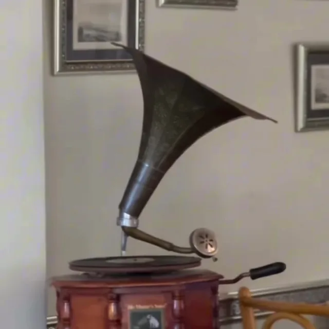 Salonda eski bir gramofon, duvarda çerçeveli fotoğraflar